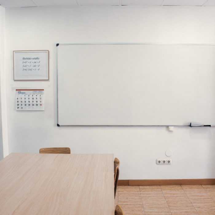 Foto de aula de la academia con una mesa grande en el centro y pizarra al fondo
